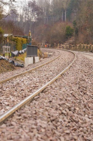 Railway tracks on a bend surrounded by gravel, along a wintry landscape, construction of the