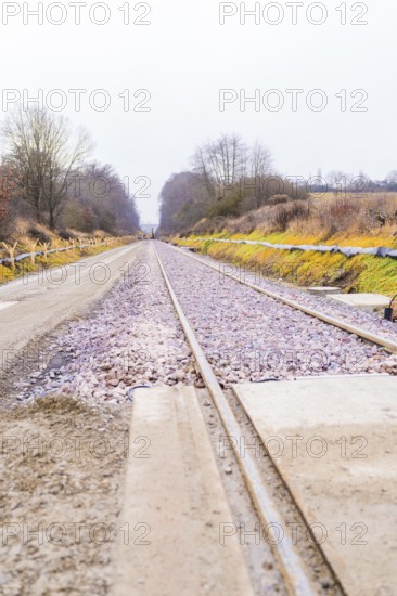 Railway tracks run in perspective through a cloudy landscape, construction of the Hermann Hesse