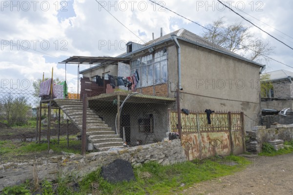 Rural building with external staircase, suspended clothing and adjacent wall, inhabited house,