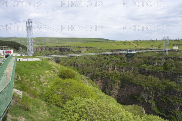 Wide landscape with modern bridge over green, rocky gorge under cloudy sky, Diamond Bridge, Diamond