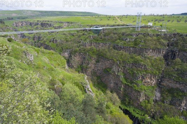 Suspension bridge stretches over a deep, green gorge with surrounding nature, Diamond Bridge,
