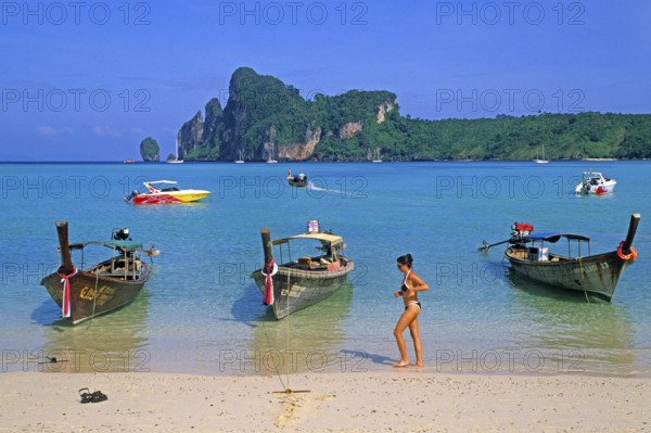 Young woman, longtail boats on the beach of Ko Phi Phi Don, two years in front of the tsunami,
