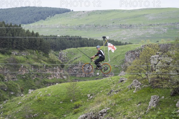 Cycling on a stretched rope across a hilly landscape with trees, Dashbashi Gorge, Khrami River,