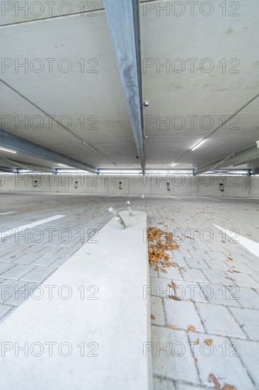 Empty parking lot with concrete floor, scattered leaves and parking space markings, parking garage