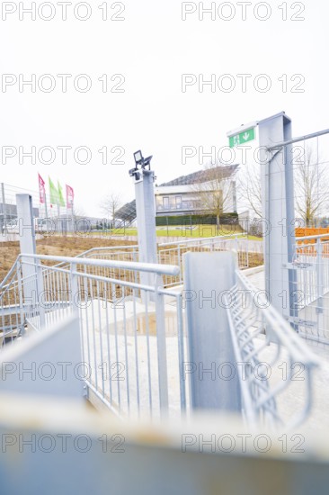 Entrance area with modern steel structure and flags, buildings in the distance, parking garage