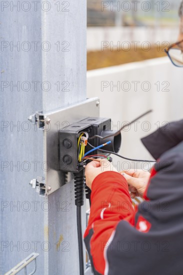 Person working on an electrical installation, cables are being connected, parking garage