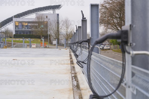Row of charging stations with a modern building in the background, parking garage construction with
