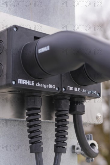 Close-up of charging stations with two black cables, mounted on metal, parking garage construction