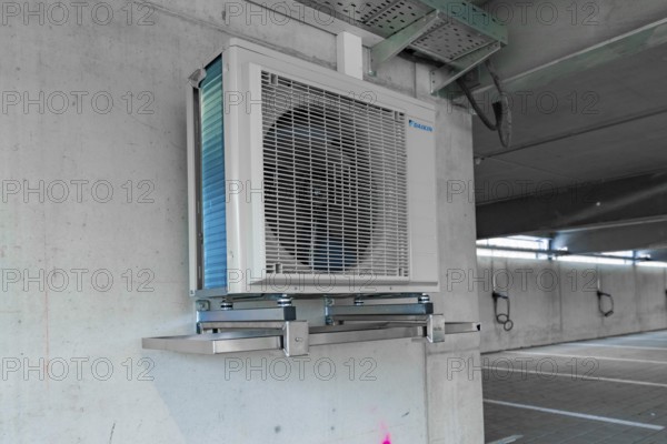 Air conditioner installed on an industrial bracket on a concrete wall indoors, parking garage