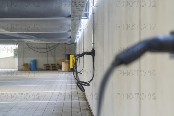 Electric charging cable on car park wall with concrete look, parking garage construction with