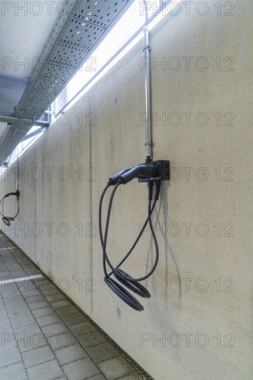 Electric charging station mounted on a concrete wall in a parking garage, parking garage