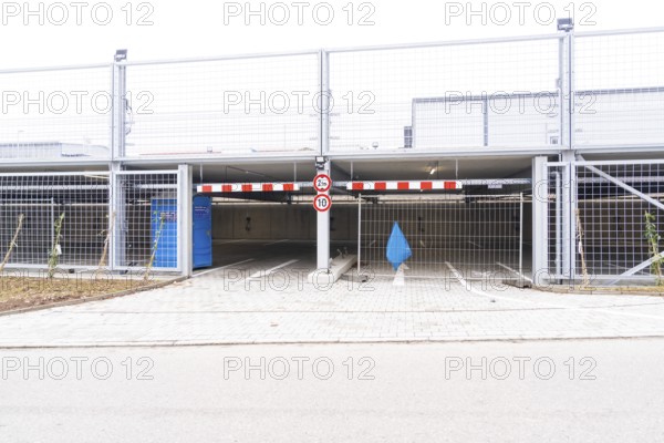 An empty parking deck with a barrier and a traffic sign. The area is secured by fences, car park