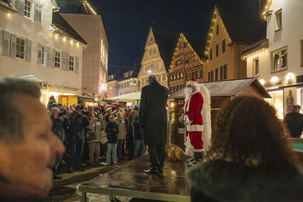 Santa Claus standing on stage in front of a crowd at night, Weihnachtsmark Nagold, LandkreiScalw,