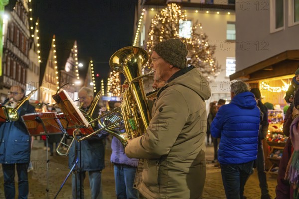 Brass players play at a Christmas market with festive lighting, Weihnachtsmark Nagold,