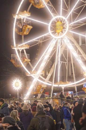 An illuminated Ferris wheel lights up the night above a busy Christmas market, Weihnachtsmark