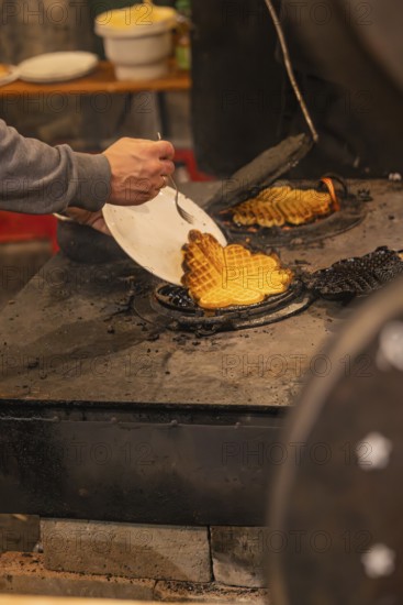 A person picks waffles baked fresh at a market from an oven, Weihnachtsmark Nagold, LandkreiScalw,
