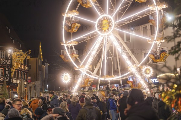 Large illuminated Ferris wheel next to a crowd at a Christmas market at night, Weihnachtsmark