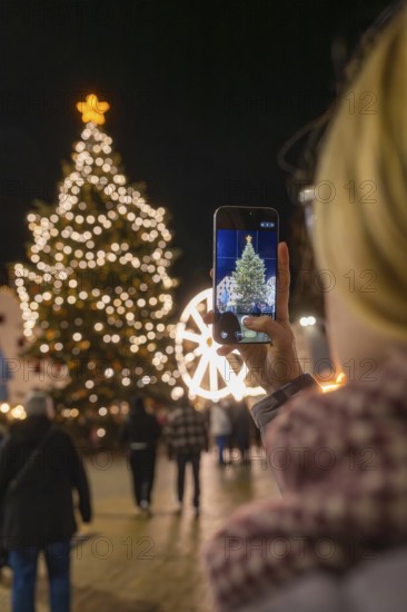 A Christmassy tree is photographed by a person with a mobile phone, Weihnachtsmark Nagold,