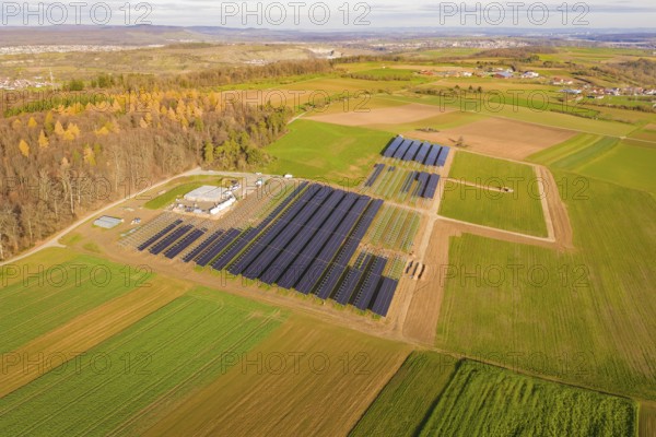 Large solar plant surrounded by autumnal fields and a village in the background, Energiewende,