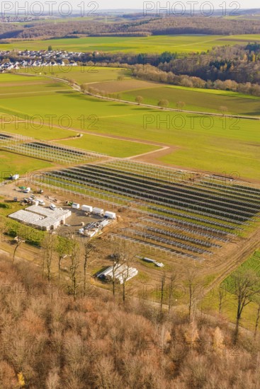 Large solar system next to buildings, surrounded by fields and forests, energy revolution,