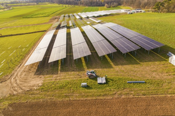 Aerial view of a solar installation site surrounded by green fields, energy revolution,