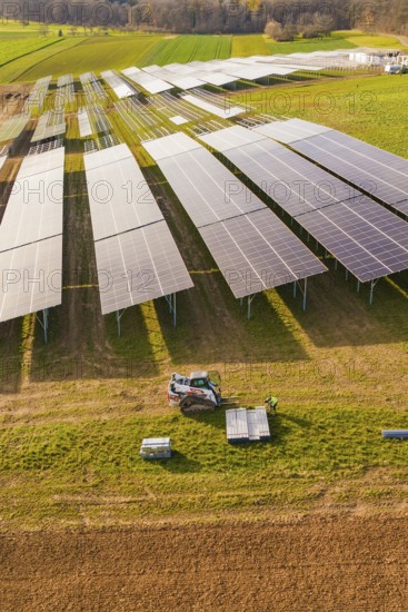 Workers install solar panels in fields with agricultural technology, energy transition,