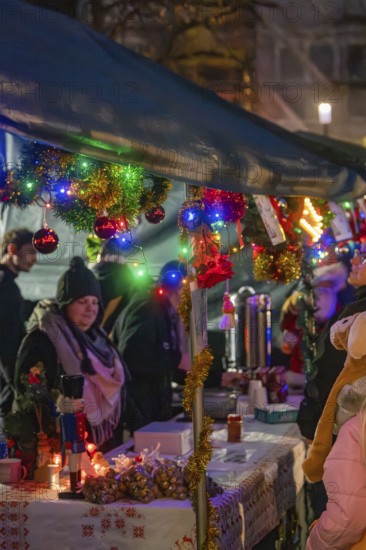 Christmas market with decorated stands and glowing lights, surrounded by people in a festive mood,