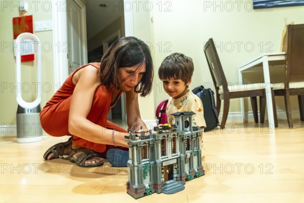 Mother and son enjoying quality time together, building a toy house in the comfort of their living