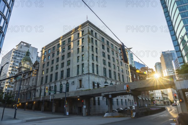 Sun is rising behind waterfront station, casting warm glow on historic building and modern