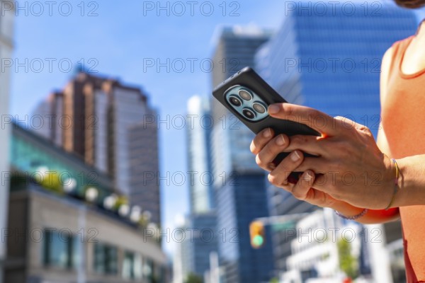 Tourist using a smartphone while surrounded by the vibrant downtown of vancouver, british columbia,
