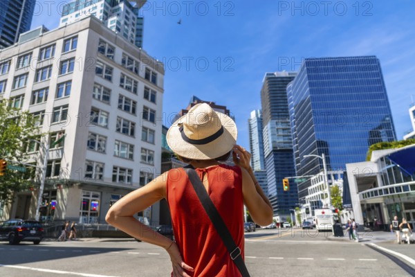 Young woman wearing a straw hat enjoying the cityscape of vancouver, british columbia, on a vibrant