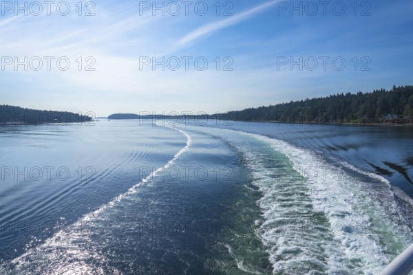 Churning white foam and turquoise water create a scenic wake as a ferry crosses the strait of
