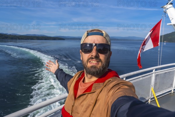 Tourist wearing sunglasses and a cap enjoys ferry trip from victoria, vancouver island, to