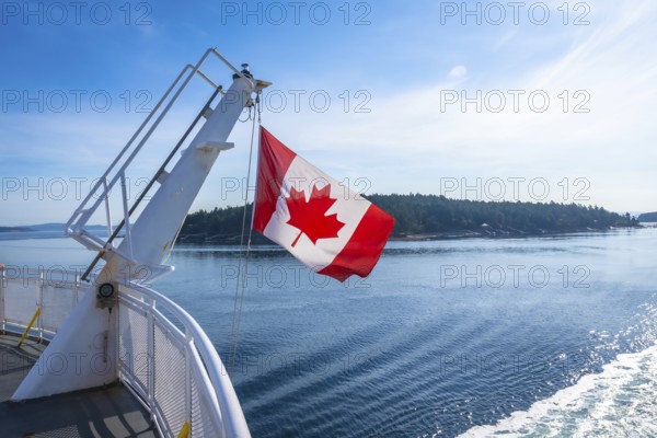 The canadian flag waves proudly from a ferry traveling between victoria on vancouver island and