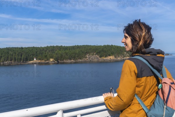 Tourist leaning on the ferry railing, enjoying breathtaking ocean views and a small island with a