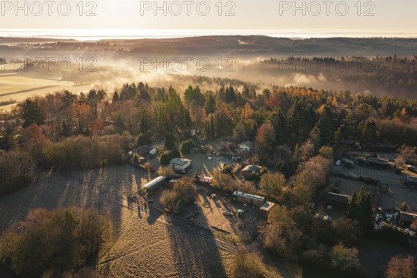Snowy village surrounded by thick forests with fog and sunrise over the hills, Gechingen, Calw