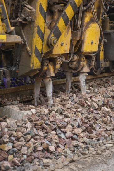 Detailed view of a gravel and track construction machine with yellow-black painting, stuffing