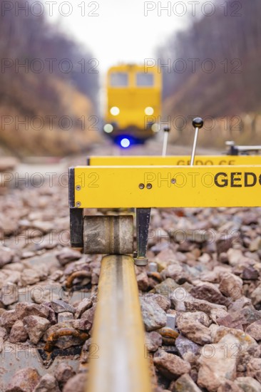Close-up of a rail surveyor, a yellow vehicle in the background, tamping machine on the Hermann,