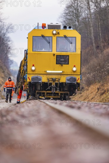 Yellow track construction equipment on rail road, worker watching work, stuffing machine on