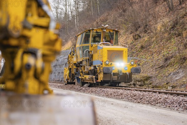 Rail construction machine in use on railroad tracks, indicated blur in the foreground, stuffing