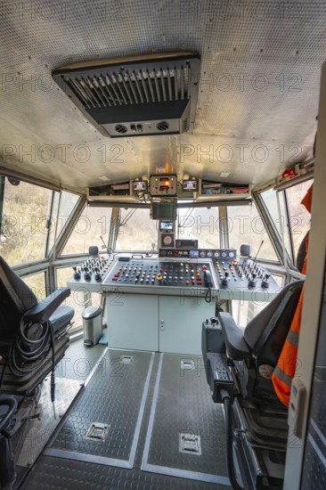 Spacious train driver's cab with comprehensive control panel and seating, stuffing machine on