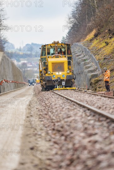 Machine and worker on rails during construction work in a rural area, tamping machine on Hermann,