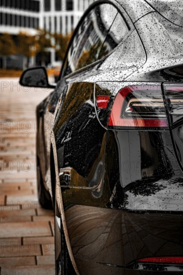 Close-up of a black vehicle with a rain-wet surface in an urban environment, Deer E-Carsharing,