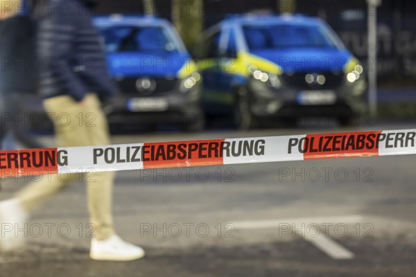 Flutter tape with the inscription police barrier. Behind them, police vehicles. Stuttgart,