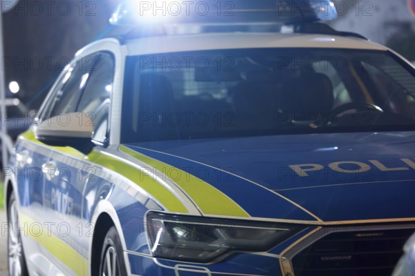 Symbolic image of a police operation: police emergency vehicle with flashing blue lights (digitally