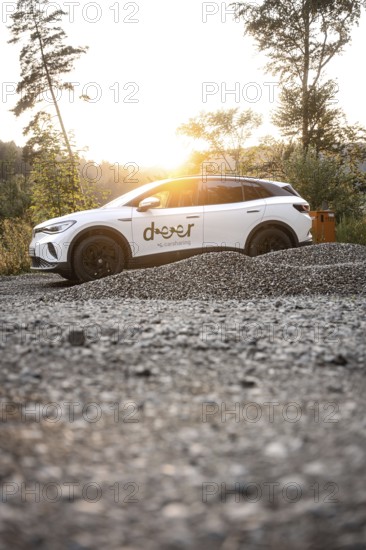 White car at sunset on gravel surrounded by nature, peaceful atmosphere, VW ID4 electric car, deer
