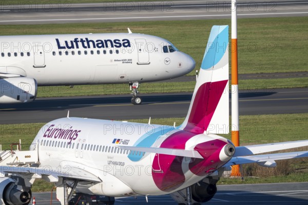 Lufthansa Airbus A321-200 on taxiway for takeoff, Eurowings Airbus parks outside position,