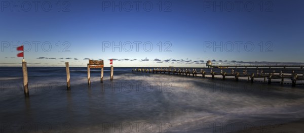 Wooden sign in the sea with inscription Zingst and Holzsteg, panorama, long exposure, evening