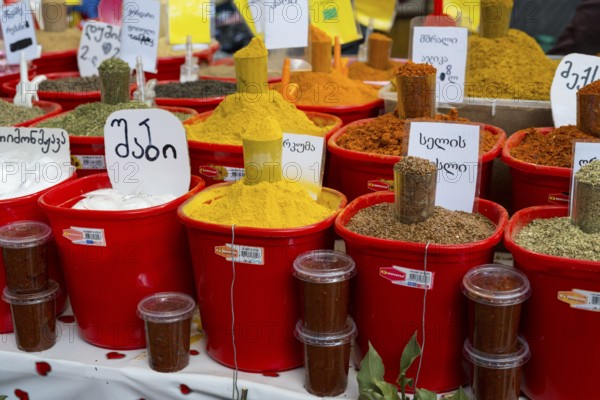 A colorful market stand with red buckets full of various spices and Georgian labels, Akhaltsikhe