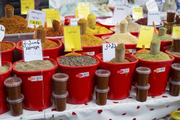 A market stall with red buckets full of colorful spices and Georgian lettering, Akhaltsikhe market,